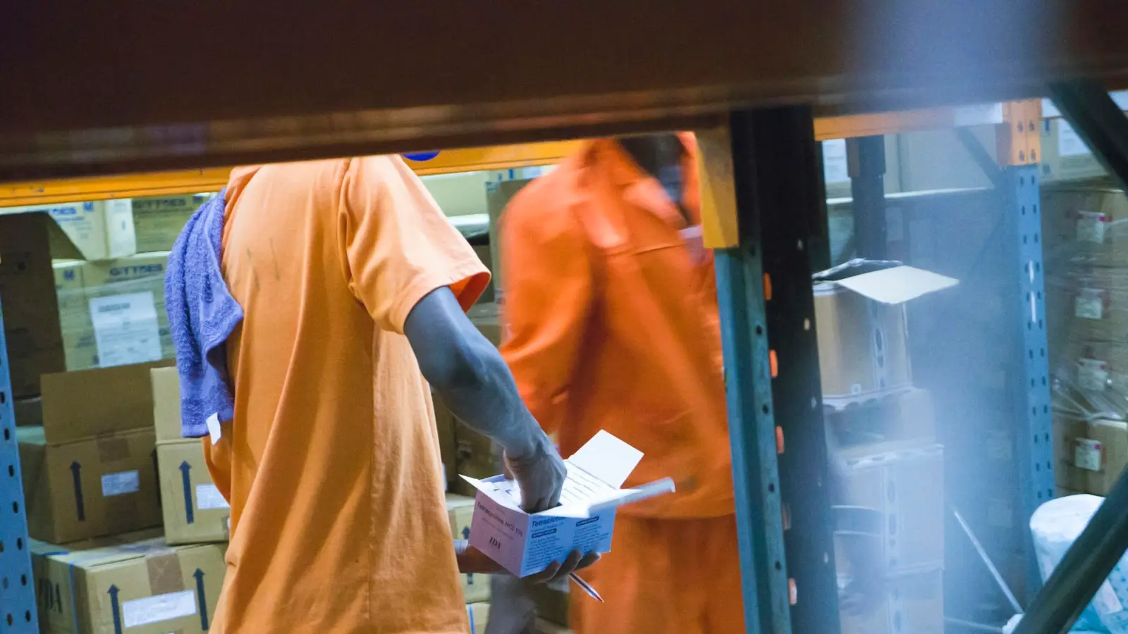 A worker holding a medicine carton in a supply store room
