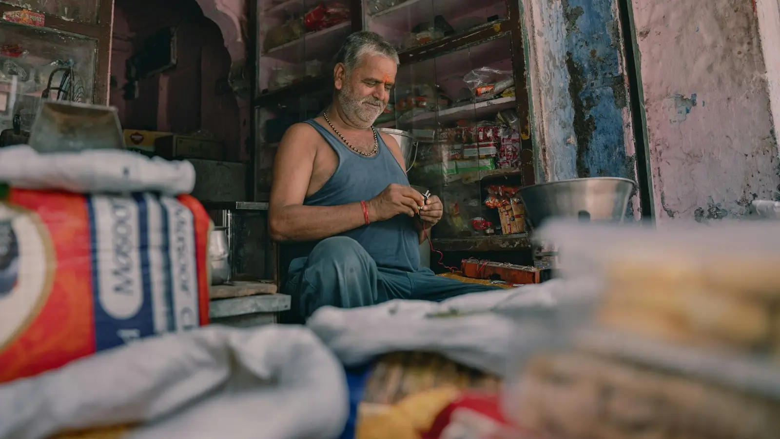 An elderly shopkeeper sitting in his small, old shop
