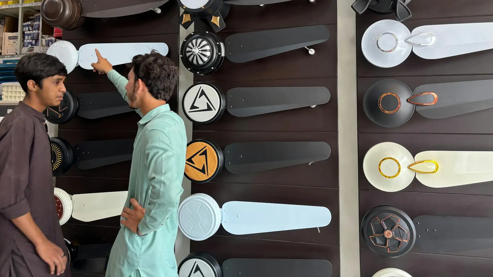 Two customers choosing a ceiling fan in an appliance shop