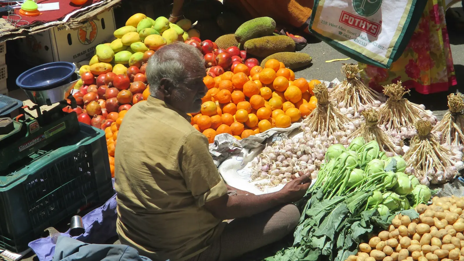 A vegetable seller with fruit and vegetables piled on his stall