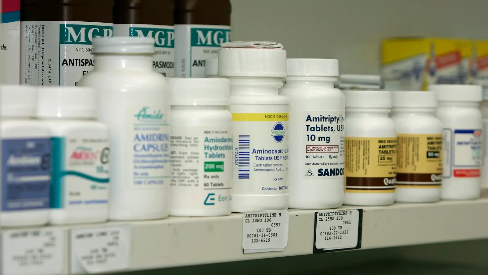 A pharmacy shelf lined with white medicine bottles