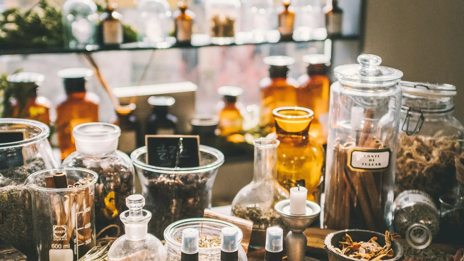 Glass jars and copper pots of dried herbs on a shop table